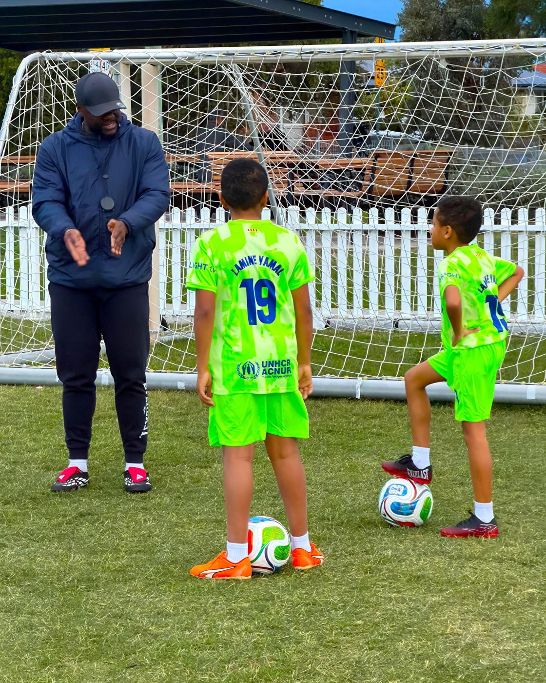 Coach talking through a drill with two players at the goal